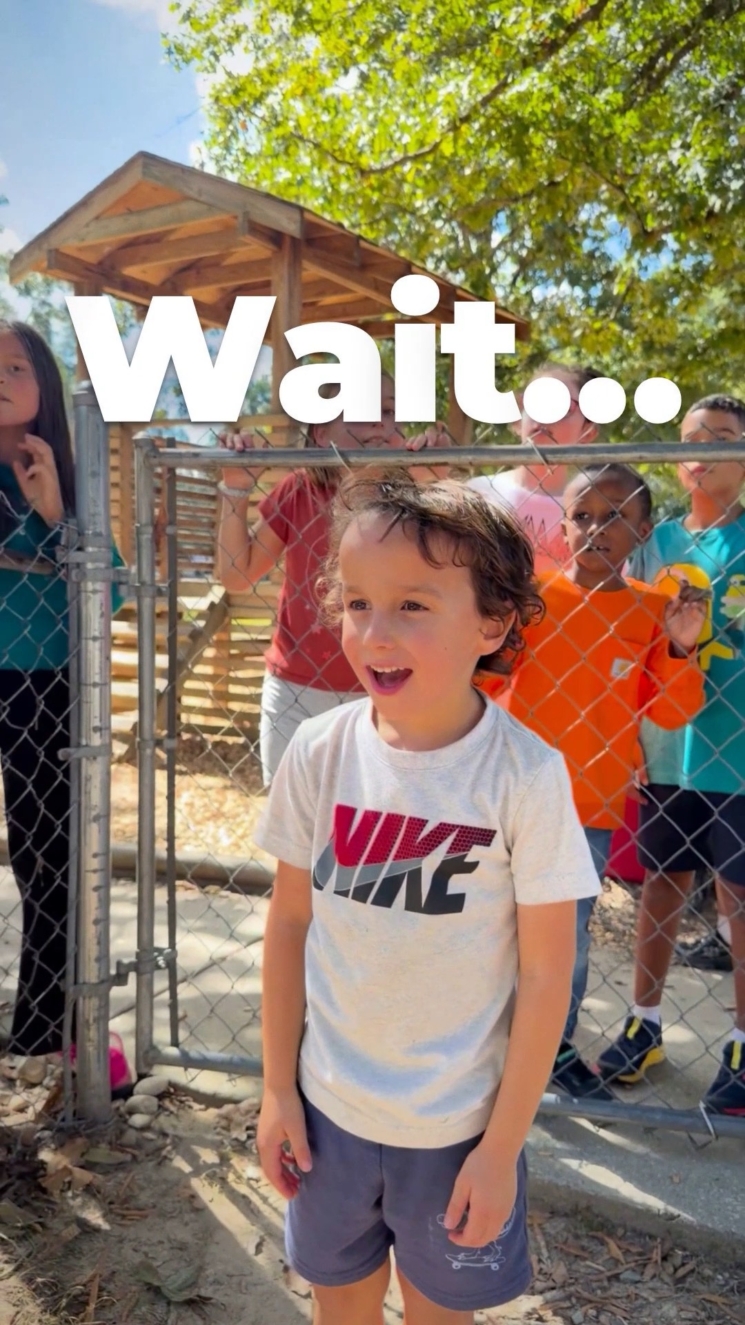 An excited student by a fence with classmates, waiting for special visitors